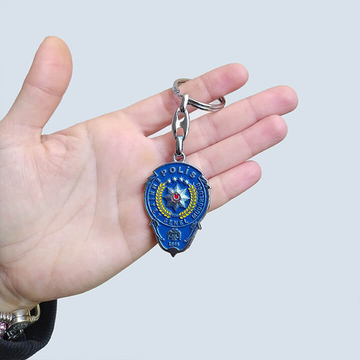 Polis Logosu Hediye Anahtarlık, dayanıklı metalden üretilmiş ve polis logosuyla kişiselleştirilmiştir. Şık ve anlamlı tasarımıyla, polis memurlarına veya teşkilata gönül veren sevdiklerinize özel bir hediye seçeneği sunar.